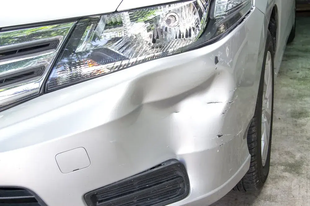 Dent and scuff damage on a silver front bumper